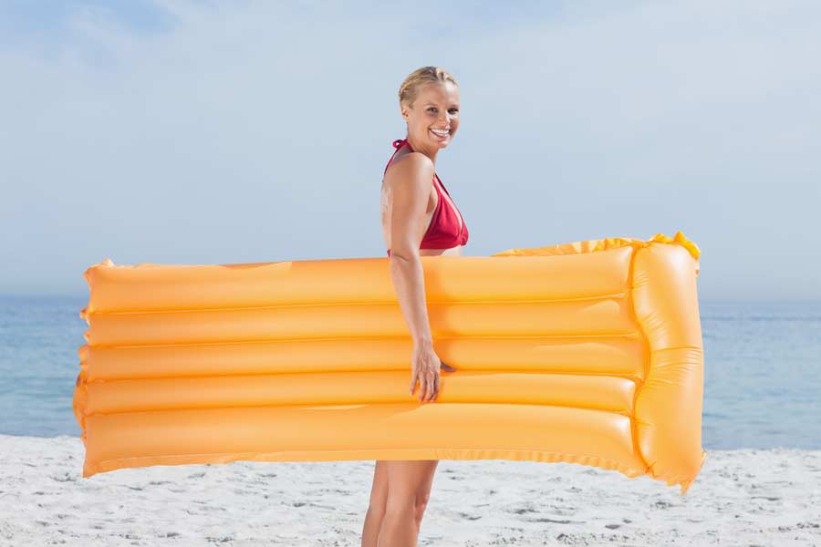 Frau mit gelber Luftmatratze am Strand (de.depositphotos.com)